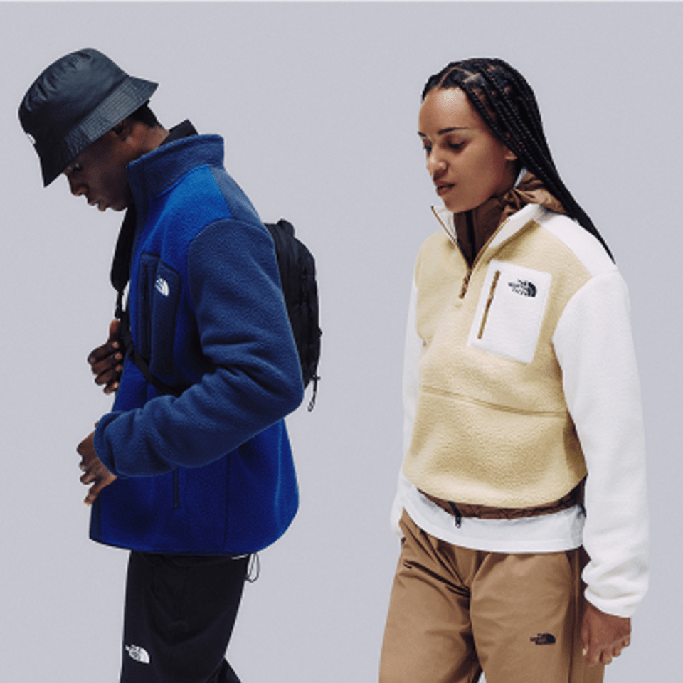 woman and man looking down in studio shot wearing fleeces by The North Face.