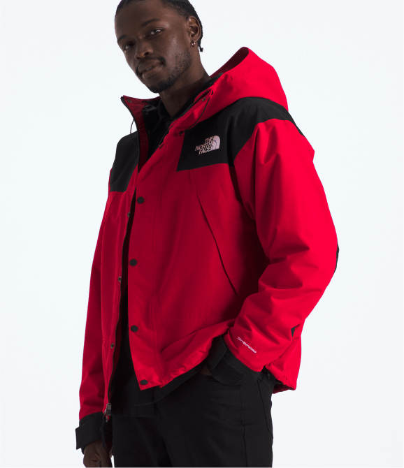A man wearing a snow jacket from The North Face standing in front of a grey background.