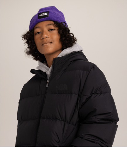 A young boy wearing a purple beanie and puffy jacket from The North Face.