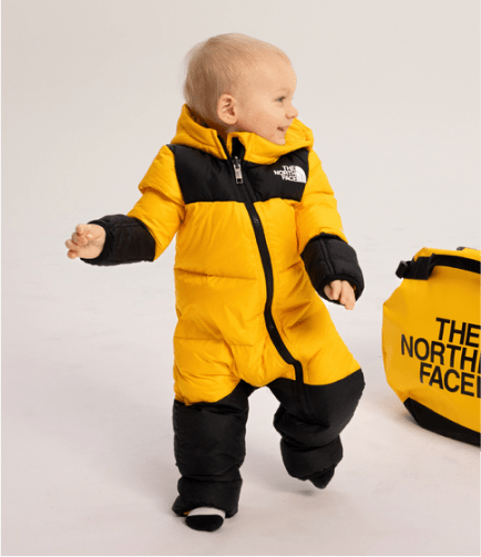 A small child walking in a puffy one piece from The North Face.