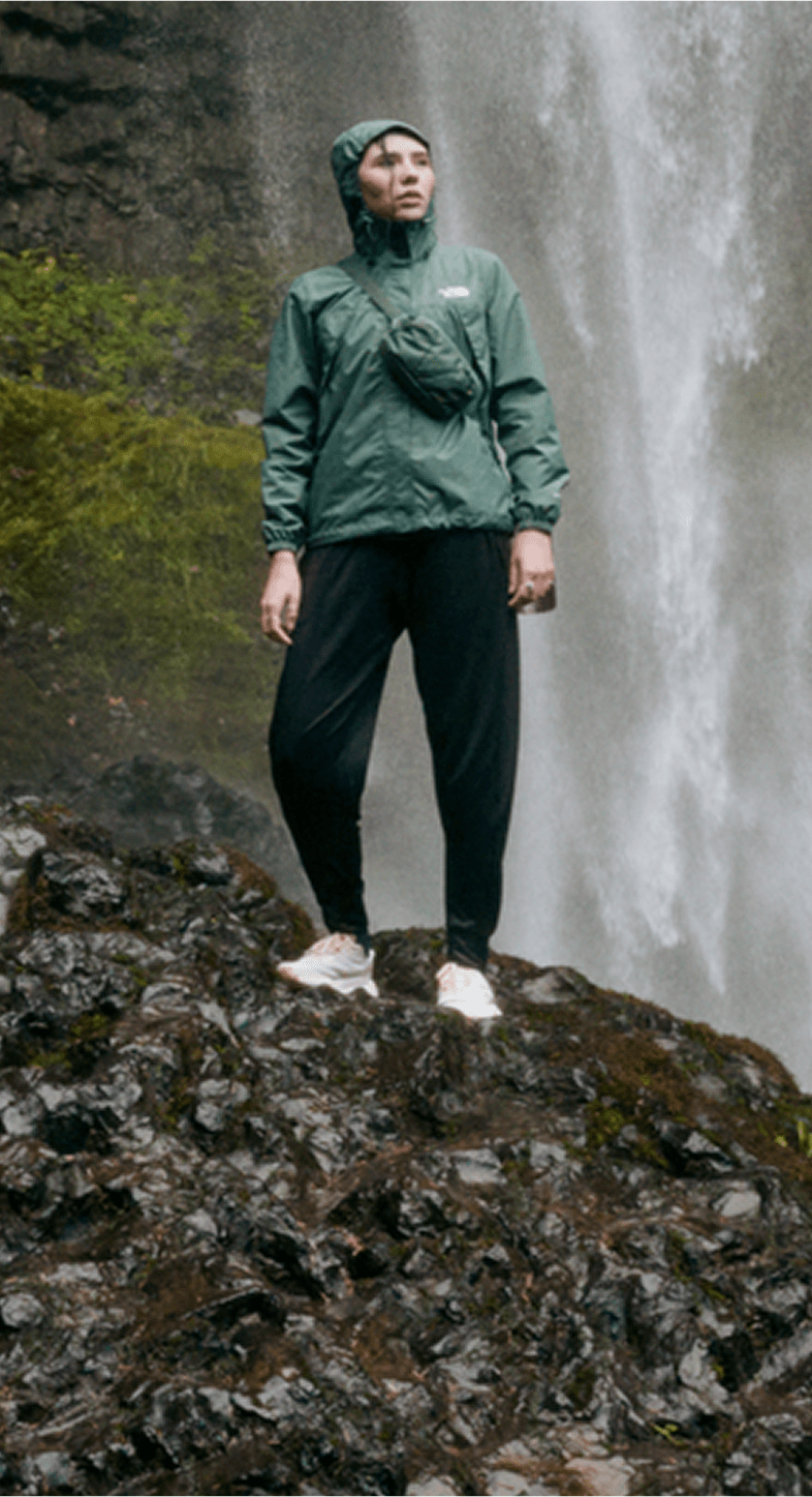 Woman standing near a waterfall with a rain jacket from The North Face