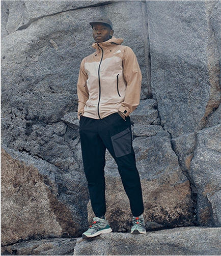 Man standing in front of a rock wall wearing a jacket from The North Face.