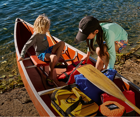 Two children in their The North Face gear explore in a canoe.