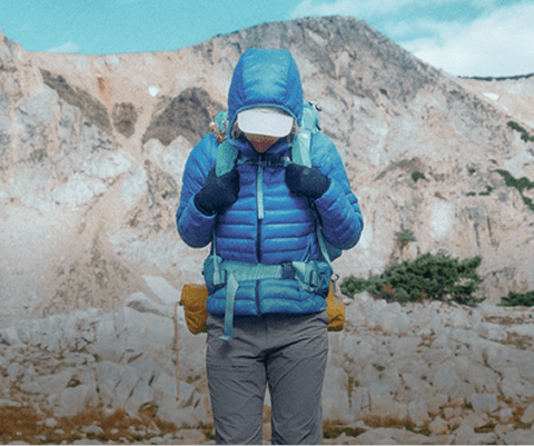 A woman hikes in rocky terrain in her The North Face gear.