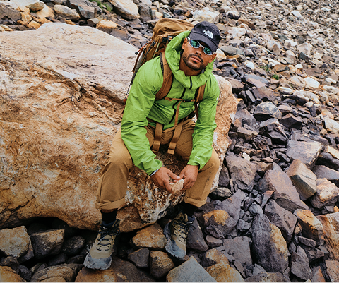 A man sits in rocky terrain in his The North Face gear.