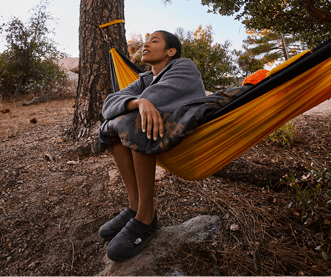 A woman sits in her The North Face hammock and fleece.