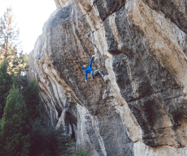 A man in The North Face gear scales the face of a rock.