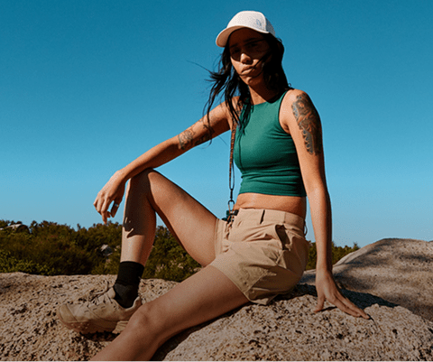 A woman in The North Face shorts sits on a rock.