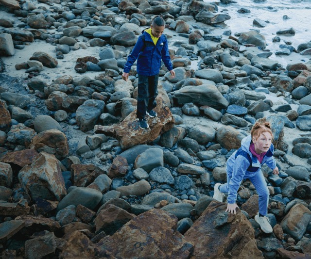 A kid hikes over challenging rocky terrain.