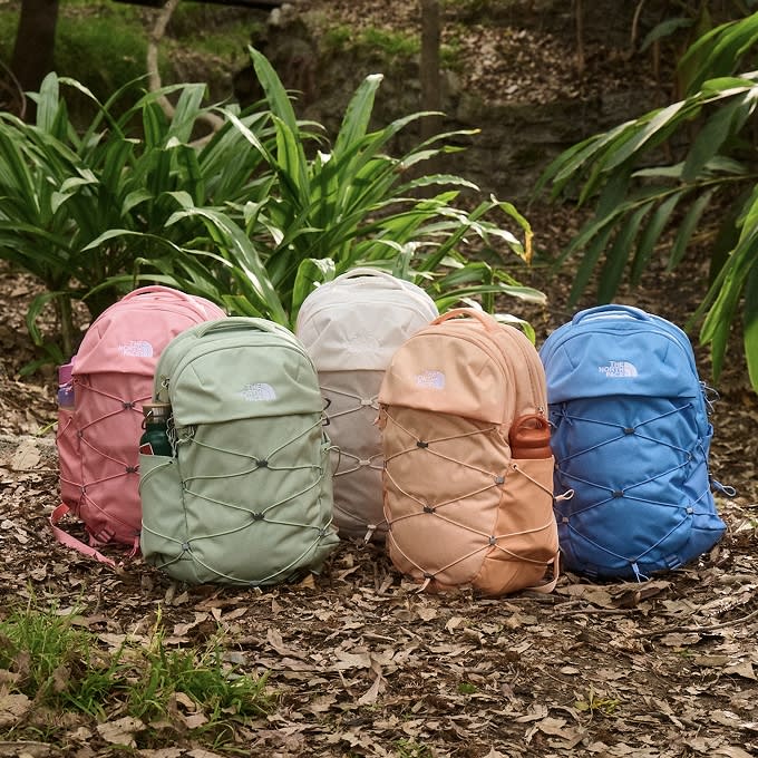 Five colorful Borealis backpacks sitting on the forest floor.