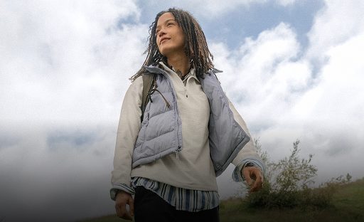 A woman wearing a white quarter zip with a vest on top. She’s walking outside. 