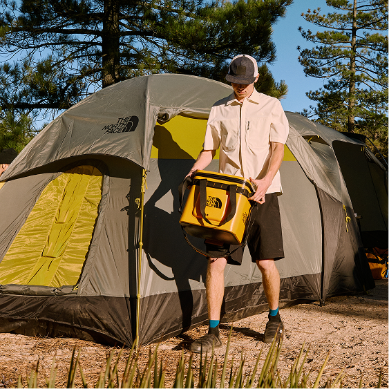 A camper carries the Base Camp Cooler near their tent.