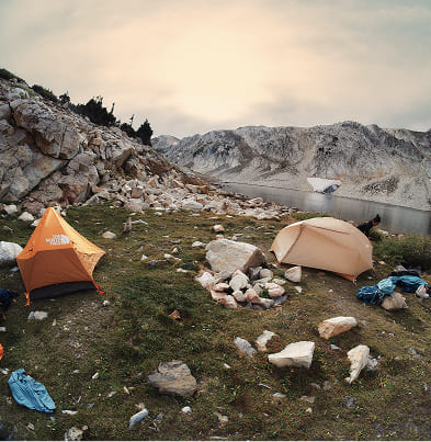 A group of campers set up their The North Face tents by a lake. 