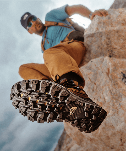 A hiker in The North Face footwear hangs off a rock.