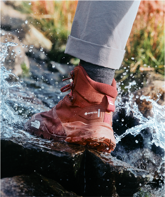 A hiker in The North Face footwear splashes through a shallow stream.