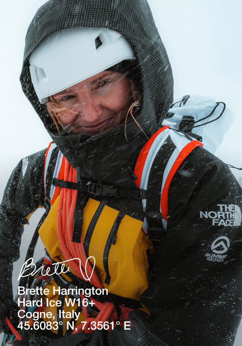 Brett in a white helmet with a hood over it smirking at the camera as it flurries around her. 