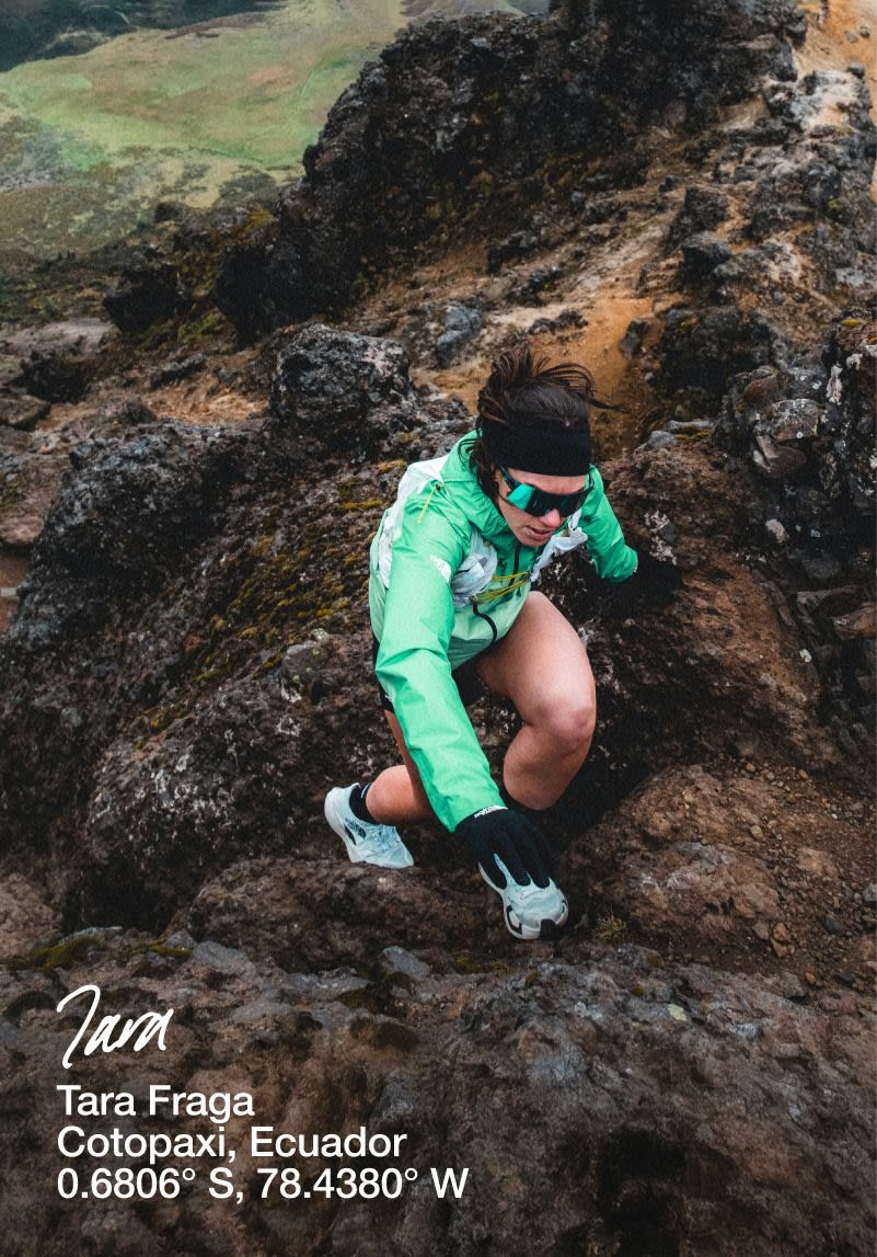 Tara ascending a rocky hill in a turquiose jacket and sunglasses. She has a high knee, it almost looks as though she’s hiking. 