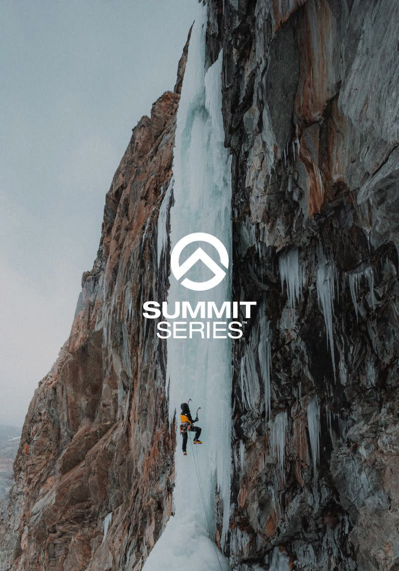A wide shot of an ice climber ascending an ice face. They look very small compared to the wall.