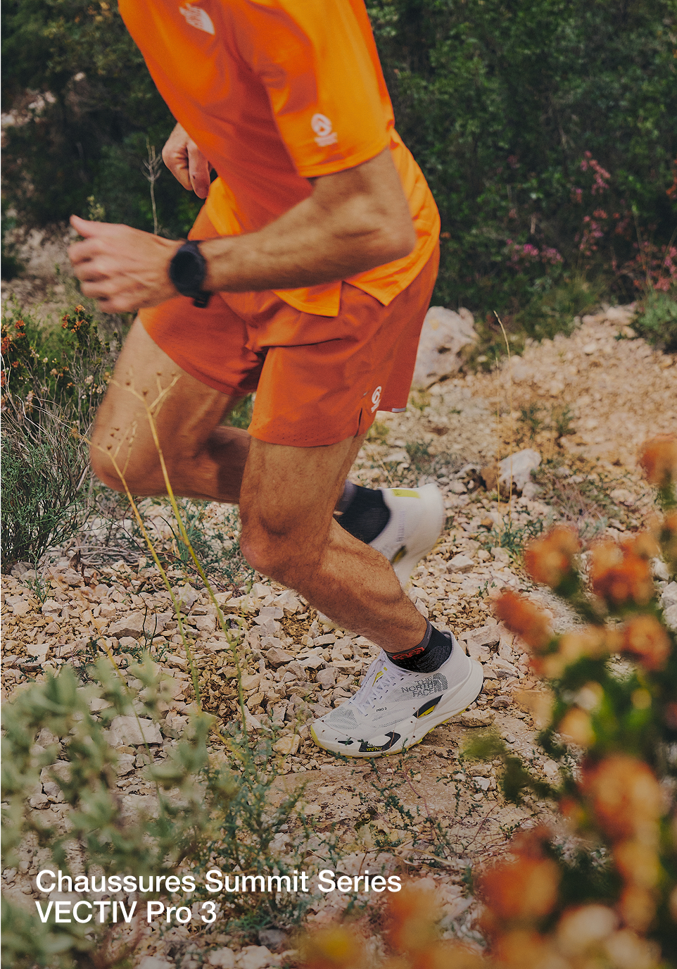 Gros plan du torse et du bas du corps de Jon alors qu'il court en montée. Il porte une tenue orange, une montre noire et aucun gilet de course.