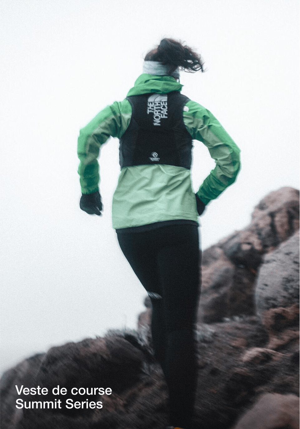 Une image de Tara de dos alors qu'elle court en montée avec une veste turquoise et un gilet de course noir.