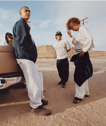 A group of people standing near a vintage car in the desert wearing The North Face Red Box collection.