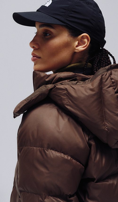 A female wearing The North Face Hydrenalite City Long Down Hooded Parka in with a side profile.