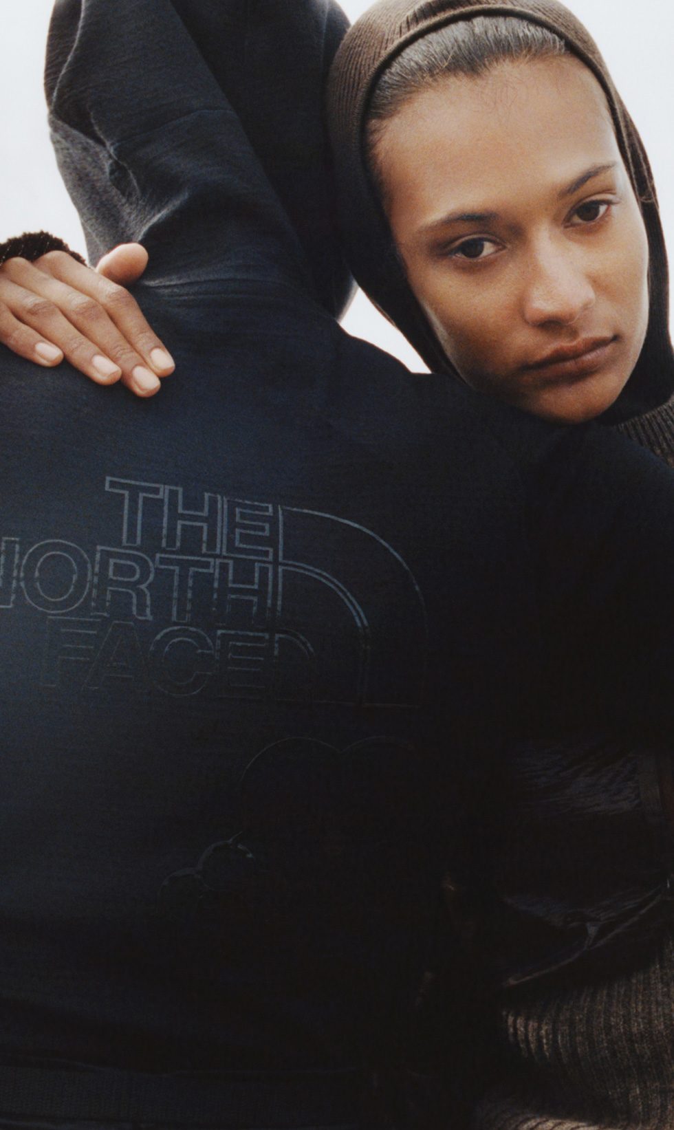 On the left: Someone with their back to the camera in a black TNF sweatshirt. On the right: Someone leaning on a shoulder with a brown hood up.