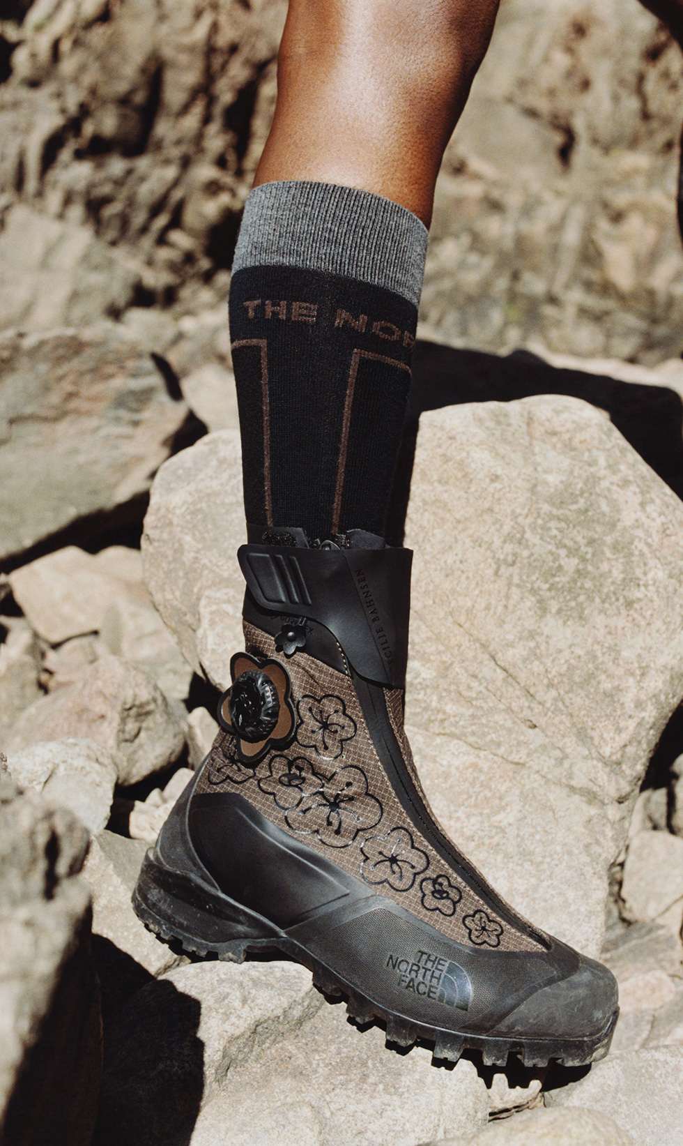 A close-up of someone wearing a brown, flowery boot and a black sock.