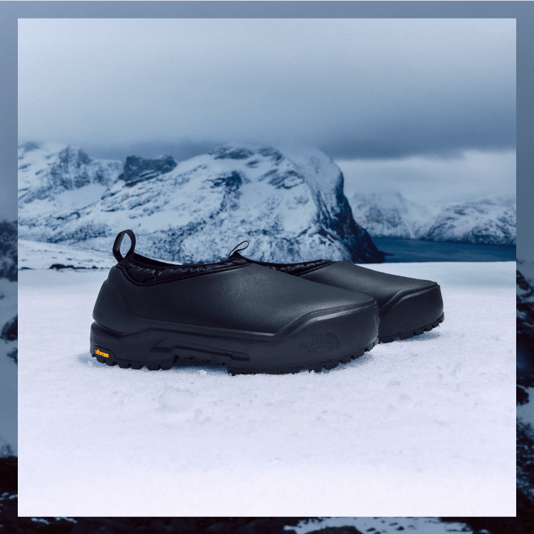 Close-up of The North Face Base Camp Waterproof Mules in black, shown against a snowy mountain landscape and icy terrain.