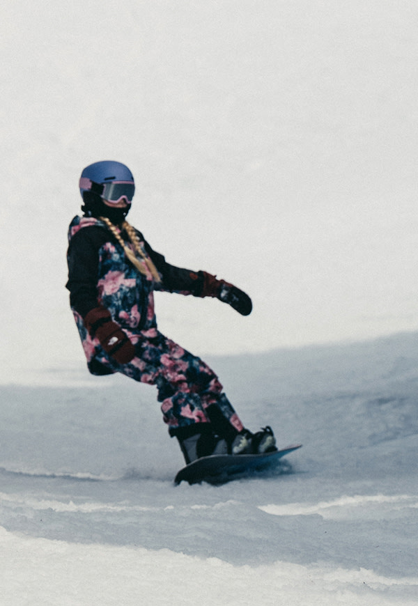wo kids snowboard down a sunlit mountain in The North Face snow gear. A close-up on the right shows the girl smiling in her helmet and goggles, board in hand, ready to ride again. 