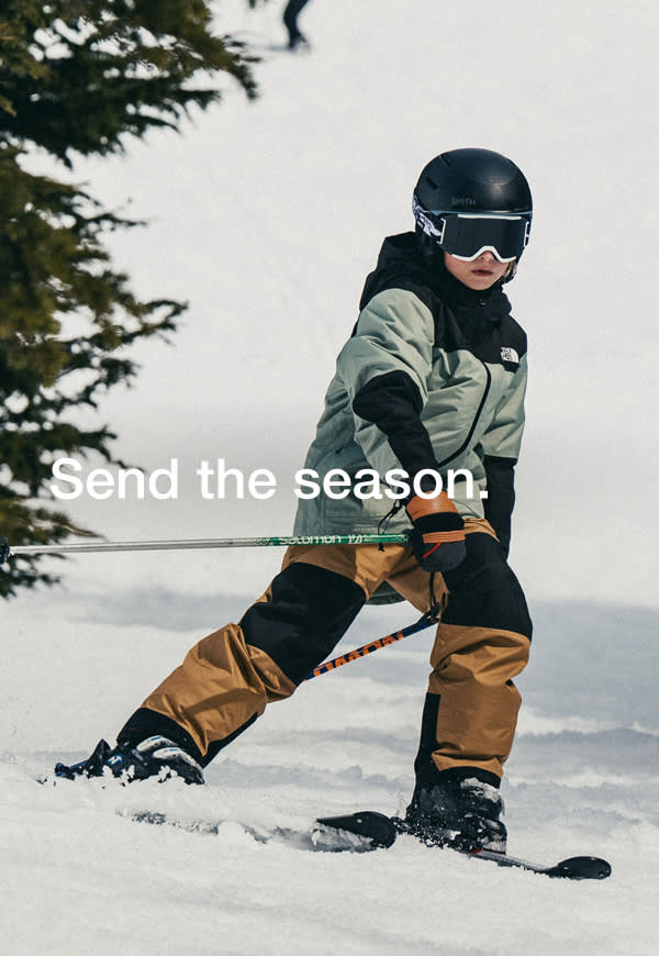 wo kids snowboard down a sunlit mountain in The North Face snow gear. A close-up on the right shows the girl smiling in her helmet and goggles, board in hand, ready to ride again. 