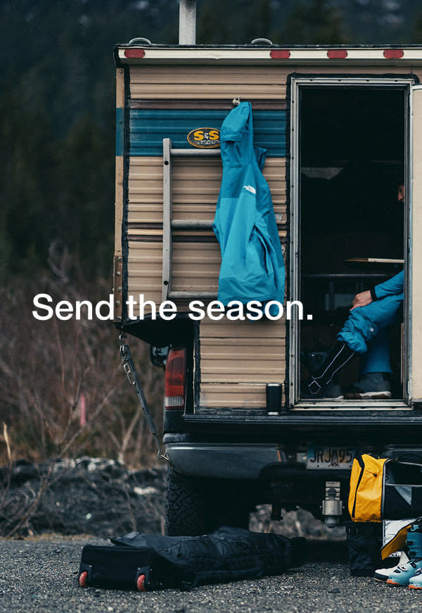 wo people walk toward the slopes, carrying The North Face Base Camp Boot Pack in Summit Gold and Base Camp Snow Roller.