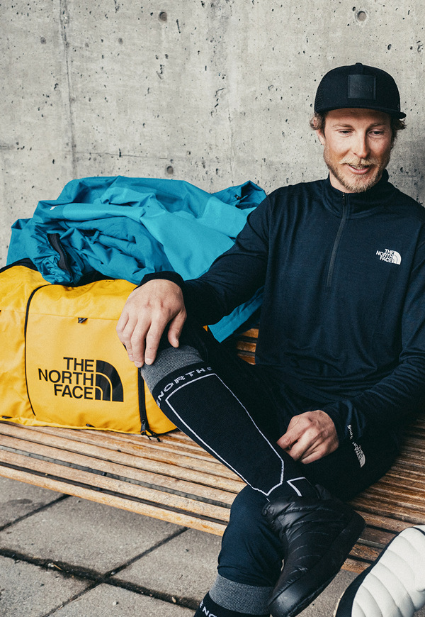 wo people walk toward the slopes, carrying The North Face Base Camp Boot Pack in Summit Gold and Base Camp Snow Roller.