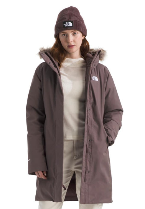 A woman in a purple Arctic Parka unzipped with a matching beanie. 