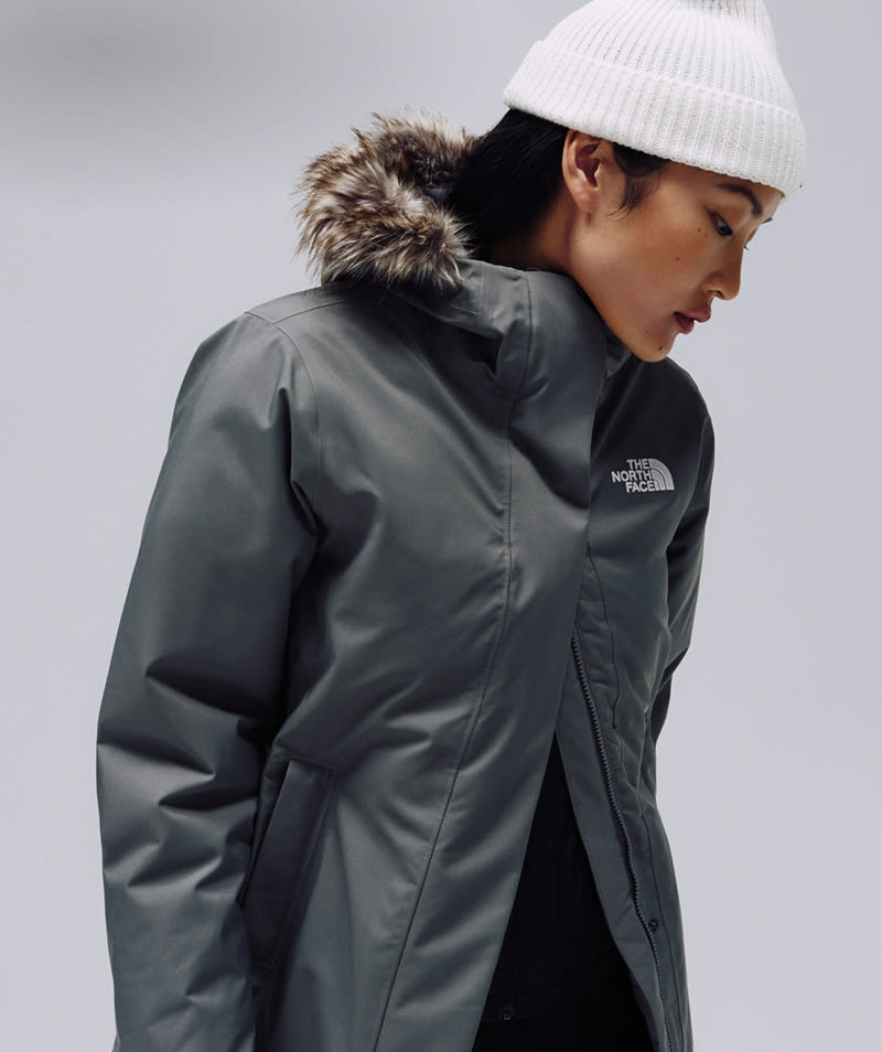 Female model wearing The North Face Arctic Parka in Smoked Pearl, in a cool-toned studio setting.