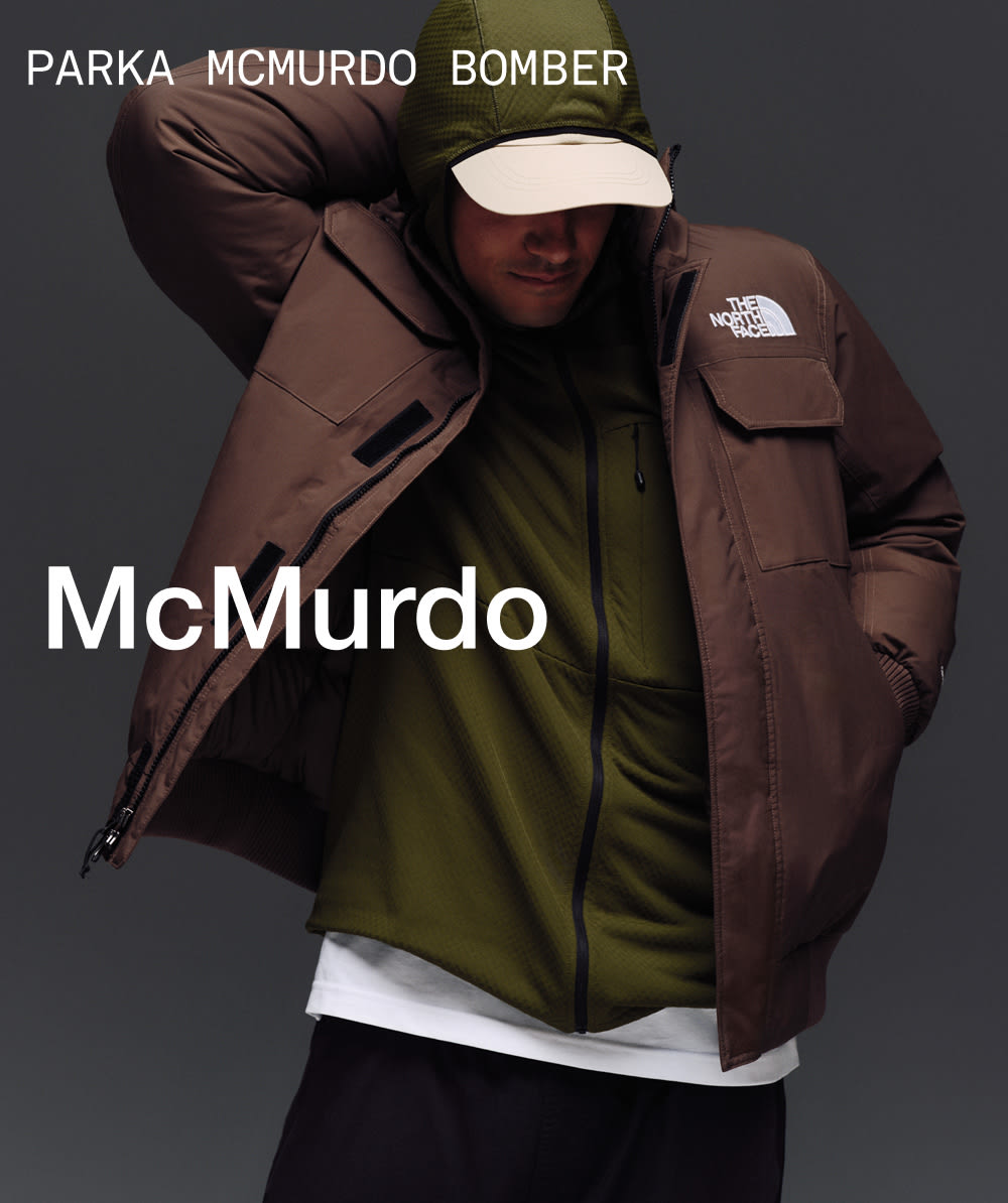 Un mannequin avec la main derrière la tête qui porte un blouson McMurdo dans la couleur brun fumée par-dessus un haut à capuchon vert. 