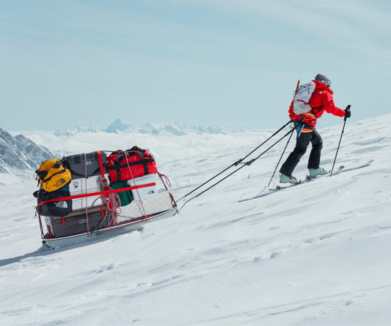 Un athlète tirant un traîneau chargé de bagages et d'équipement en haut d'une colline