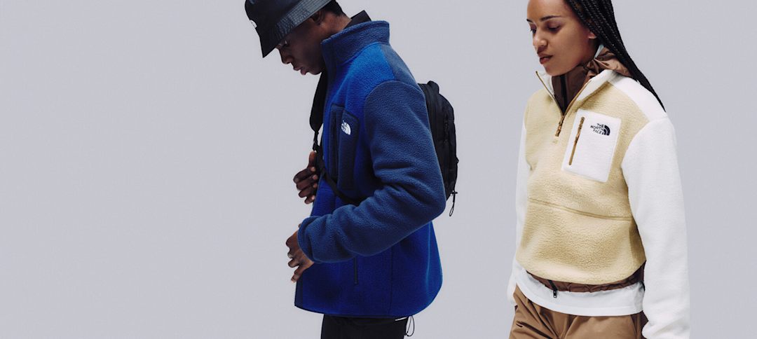 A man in a blue fleece and bucket hat with a cross-body bag facing left, and a woman white/beige fleece with black hair also facing slightly left.