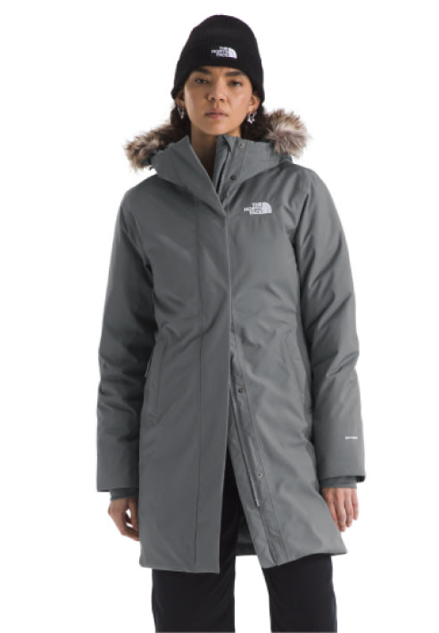 A woman in a purple Arctic Parka unzipped with a matching beanie. 