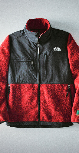 Gros plan sur la moitié inférieure d’une veste Casentino Denali par The North Face rouge et noire.