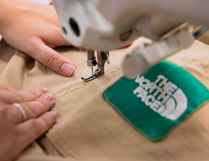 A person sewing a recycled shirt from The North Face.