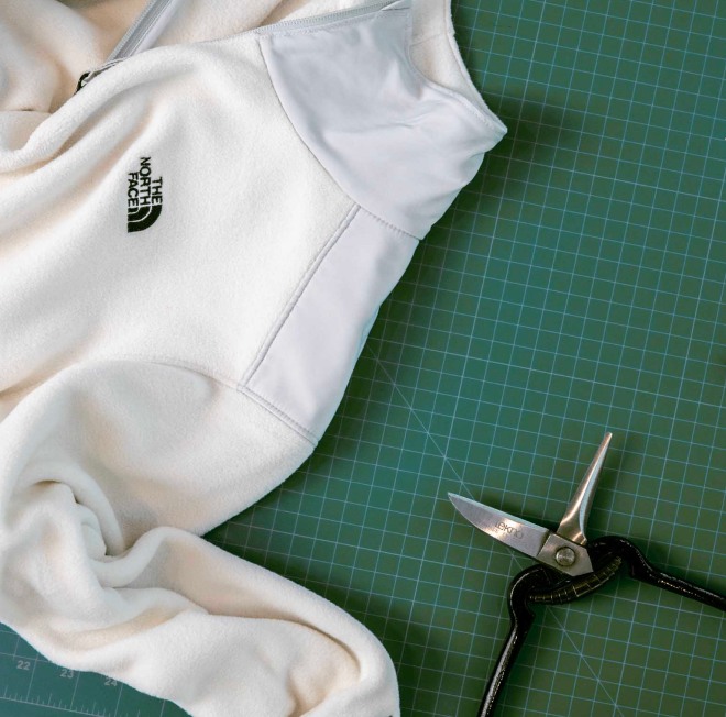 A person sewing a recycled shirt from The North Face.