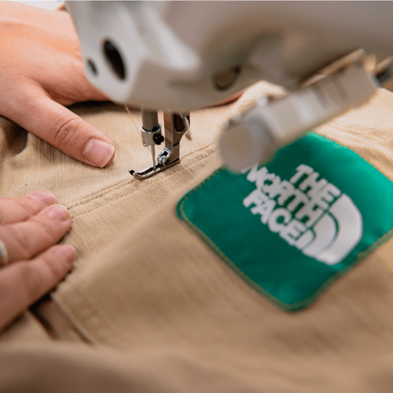 A person sewing a recycled shirt from The North Face