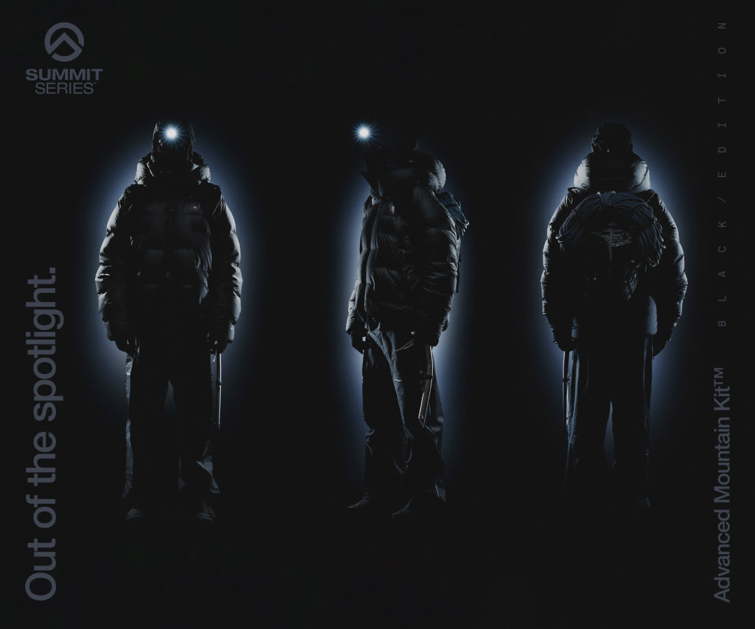 The Advanced Mountain Kit Black Edition collection including the coat, backpack, and boots on a black background.