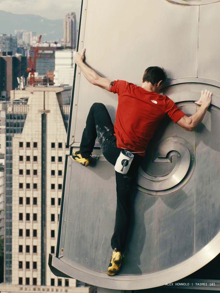 Alex Honnold wearing a red North Face shirt while free solo climbing Tapiei 101 for Netflix Skyscraper