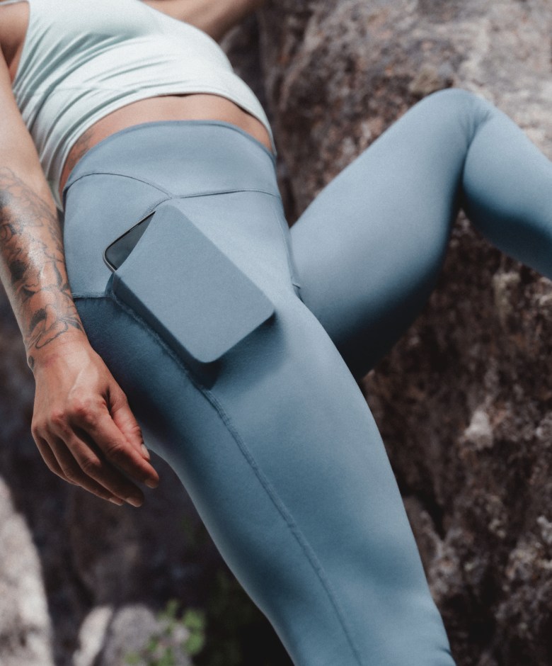 Close-up of an athlete wearing the Jaida Pocket Leggings in Granite Grey, shown against a rocky surface.