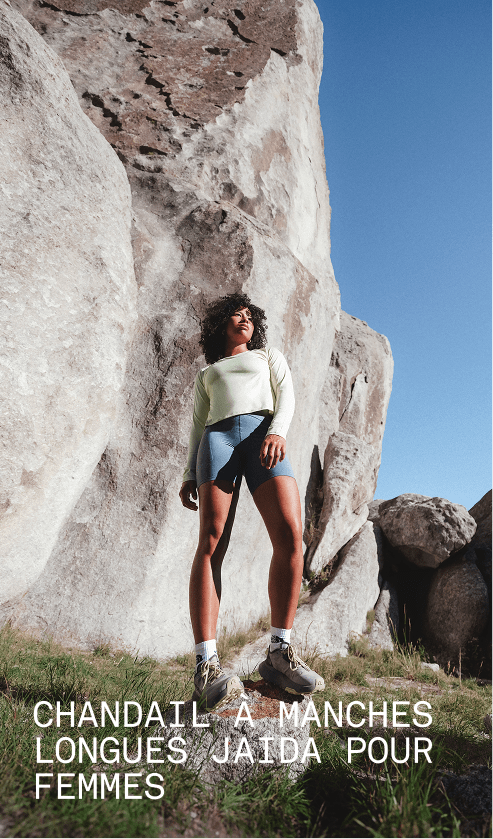 Un mannequin portant le chandail à manches longues Jaida en blanc dune se tient parmi de grandes formations rocheuses dans un décor extérieur.