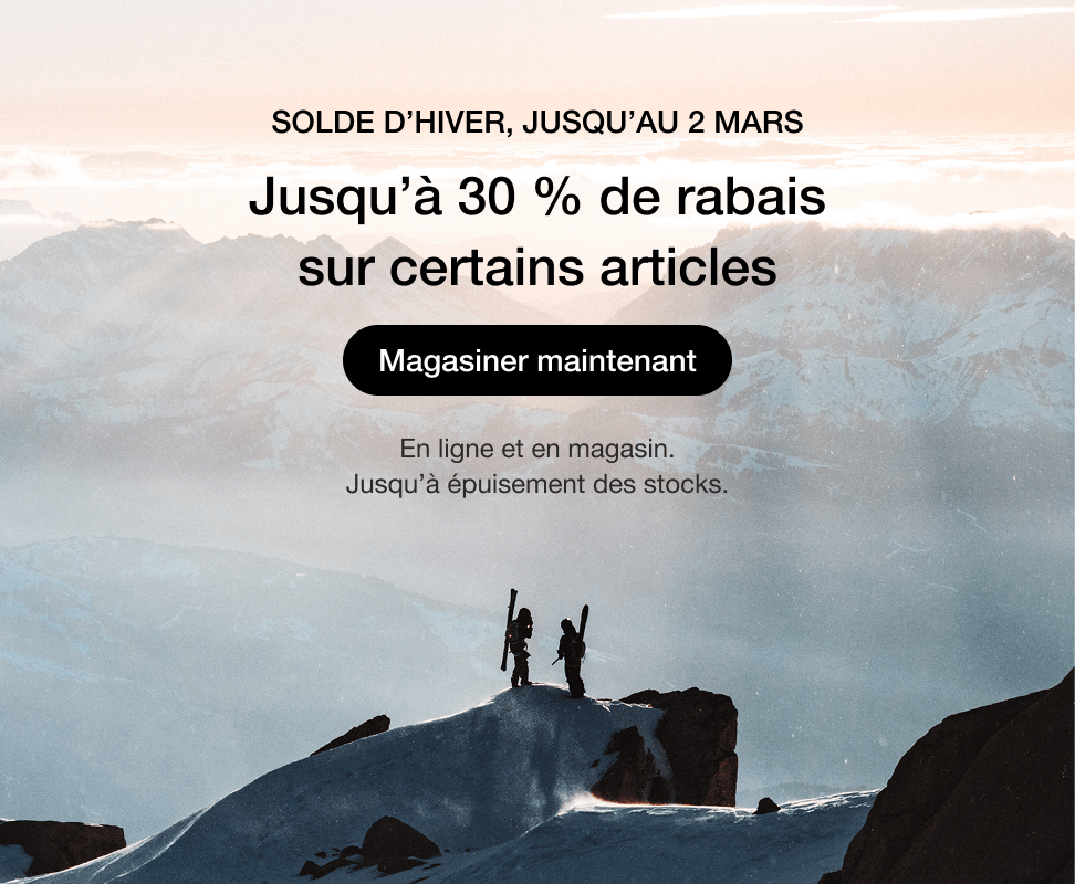 Paysage de montagne enneigée au lever du soleil avec des skieurs sur une crête.   