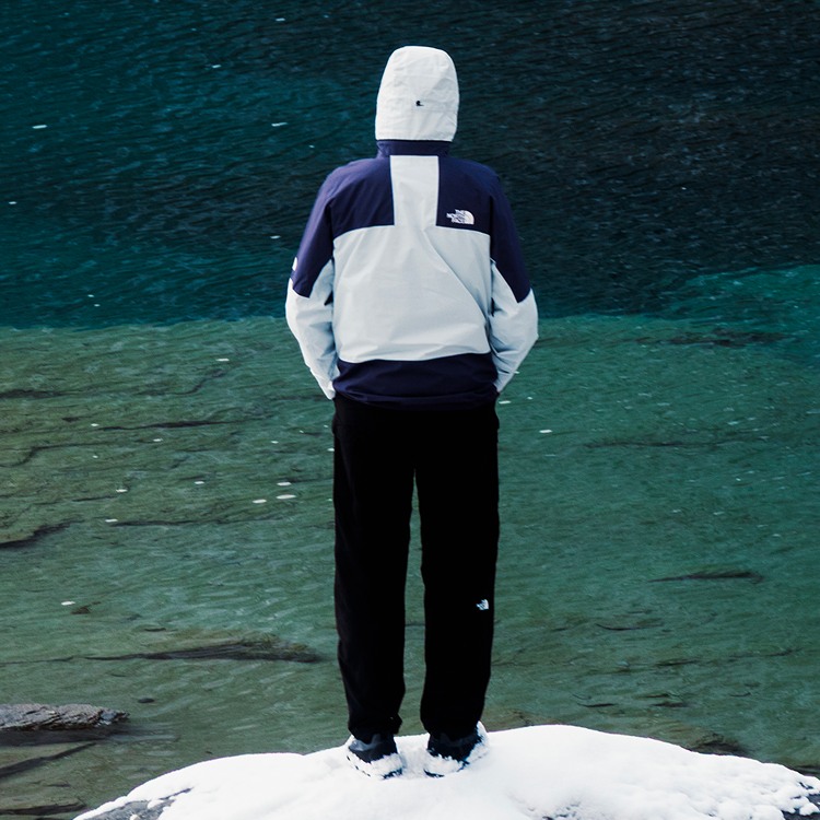Man in purple and white jacket looks at the lake.