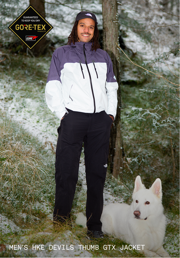 Man in purple and white jacket looks at the lake.